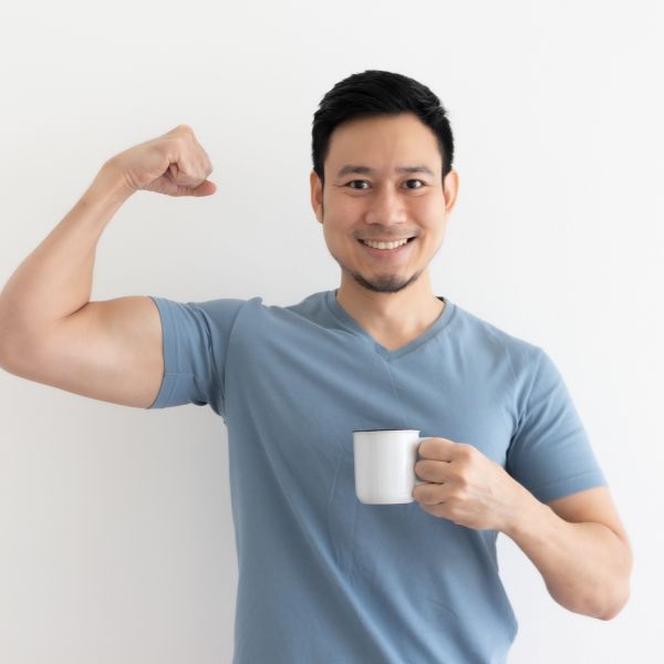 A man drinking from a mug while flexing his right arm